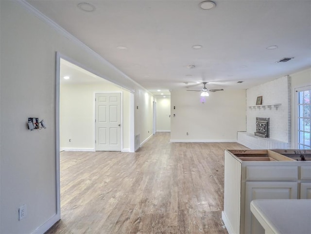 unfurnished living room featuring ceiling fan, light hardwood / wood-style floors, and ornamental molding