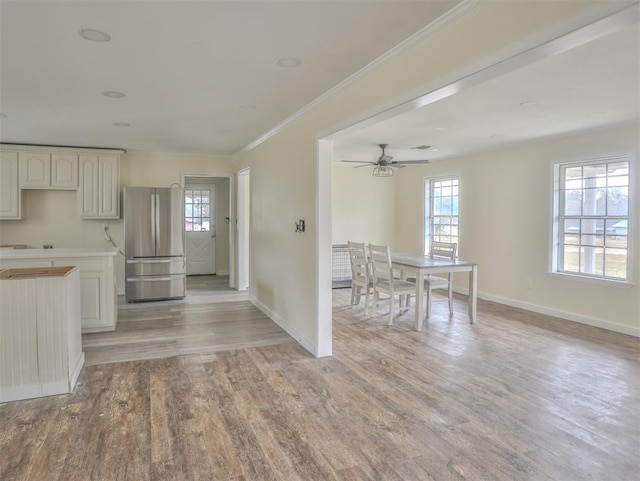 kitchen with light hardwood / wood-style floors, stainless steel refrigerator, ceiling fan, and ornamental molding