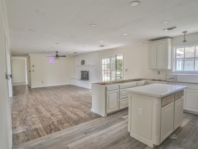 kitchen featuring white cabinets, a wood stove, a center island, and light hardwood / wood-style flooring