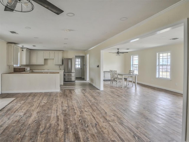 kitchen with ceiling fan, stainless steel fridge, wood-type flooring, and ornamental molding