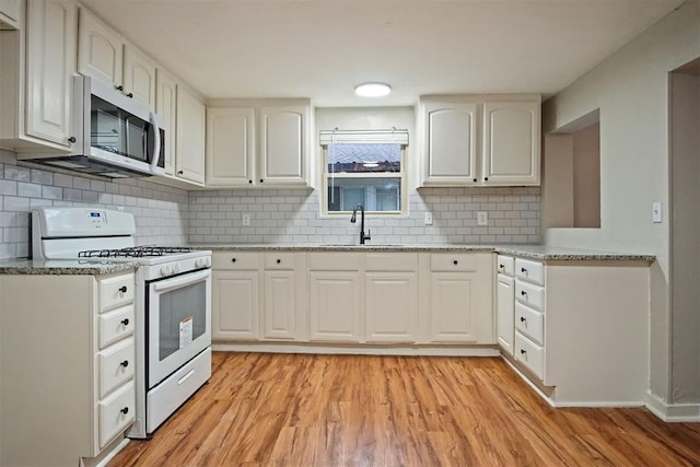 kitchen with white cabinetry, white gas range, and sink