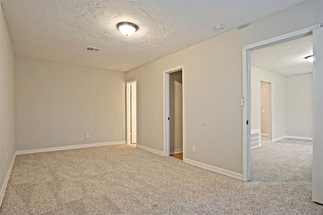 carpeted empty room featuring a textured ceiling