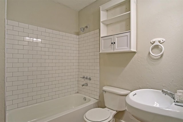 full bathroom featuring sink, tiled shower / bath, and toilet