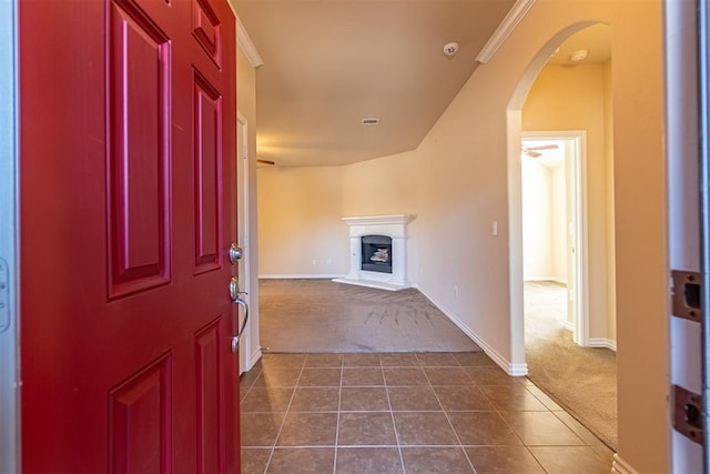 interior space featuring dark colored carpet, ceiling fan, and crown molding