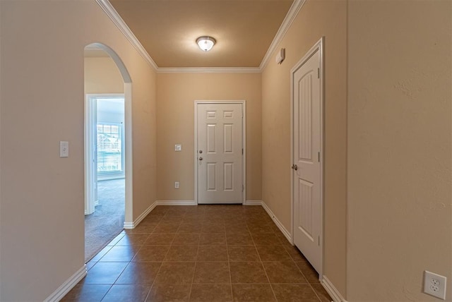 doorway with dark tile patterned flooring and crown molding