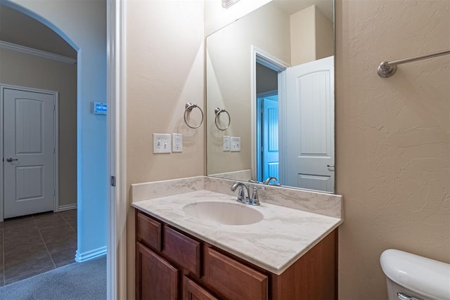 bathroom featuring tile patterned flooring, vanity, toilet, and crown molding