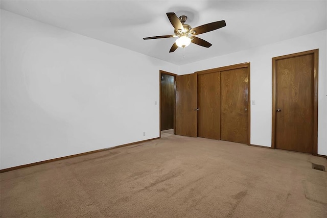 unfurnished bedroom with multiple closets, ceiling fan, and light carpet