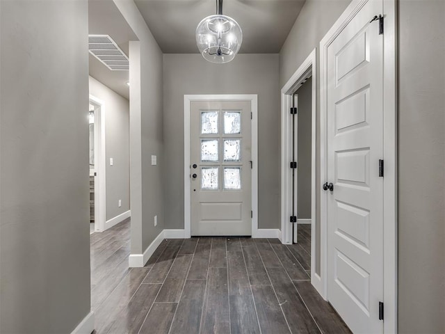 foyer entrance with dark wood-type flooring and a notable chandelier