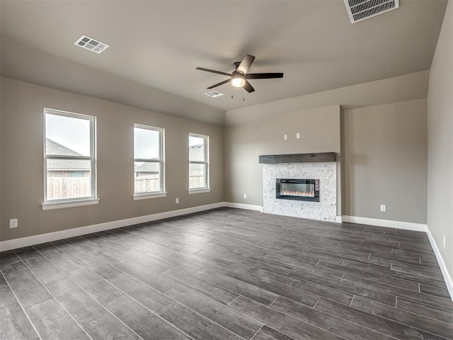 unfurnished living room with dark wood-type flooring, plenty of natural light, and ceiling fan