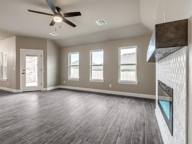 unfurnished living room featuring dark hardwood / wood-style floors, plenty of natural light, a fireplace, and vaulted ceiling