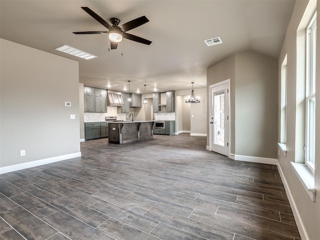 unfurnished living room with ceiling fan with notable chandelier, vaulted ceiling, and sink