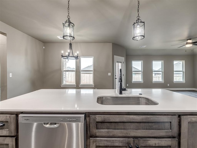 kitchen featuring sink, hanging light fixtures, stainless steel dishwasher, an island with sink, and ceiling fan with notable chandelier