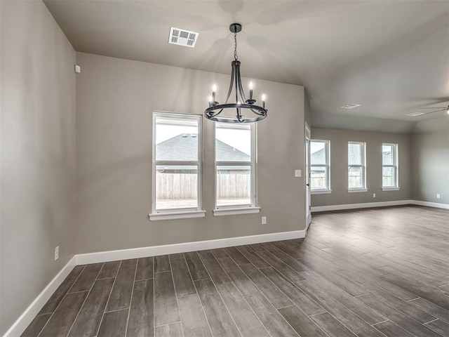 unfurnished dining area with plenty of natural light, dark wood-type flooring, and ceiling fan with notable chandelier