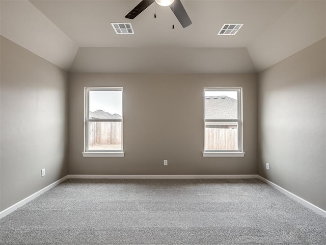 carpeted empty room featuring ceiling fan, vaulted ceiling, and a wealth of natural light