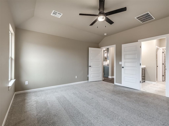 unfurnished bedroom featuring vaulted ceiling, light carpet, ceiling fan, and ensuite bath