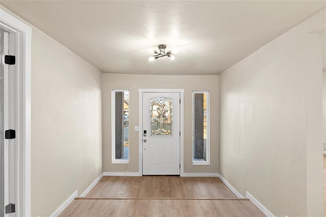 entrance foyer with light wood-type flooring, a wealth of natural light, and an inviting chandelier