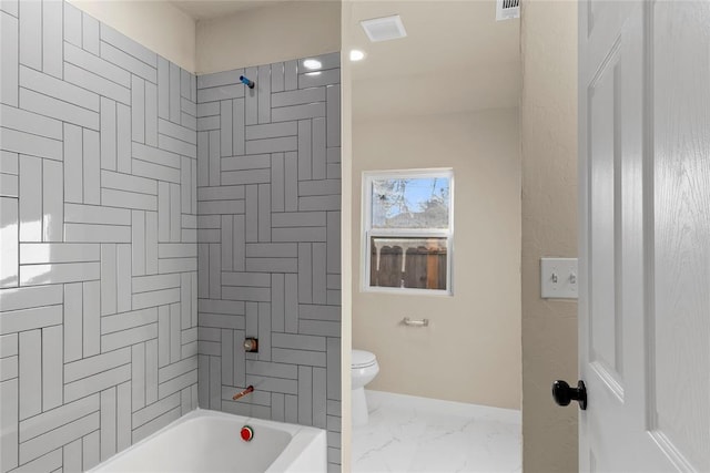 bathroom with toilet and tiled shower / bath