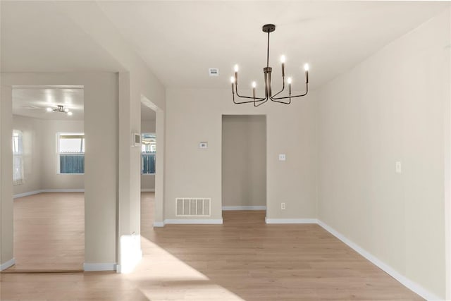 unfurnished dining area featuring a chandelier and light hardwood / wood-style flooring