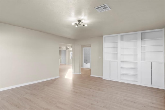 unfurnished room with light wood-type flooring and an inviting chandelier