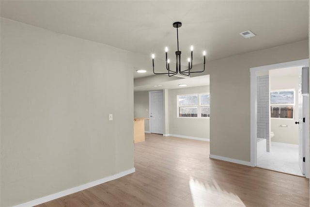 unfurnished dining area with a wealth of natural light, light hardwood / wood-style floors, and an inviting chandelier