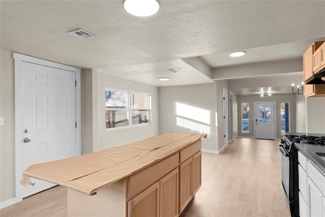 kitchen featuring a textured ceiling, light brown cabinetry, black gas range oven, and light wood-type flooring