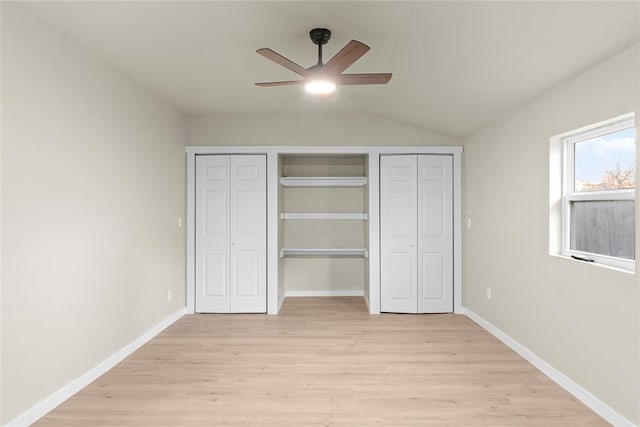 unfurnished bedroom featuring vaulted ceiling, ceiling fan, two closets, and light wood-type flooring