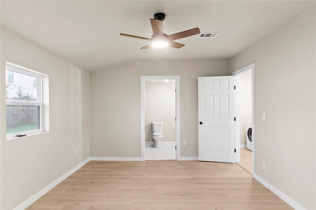 unfurnished bedroom featuring light wood-type flooring, ensuite bathroom, washer / clothes dryer, and ceiling fan