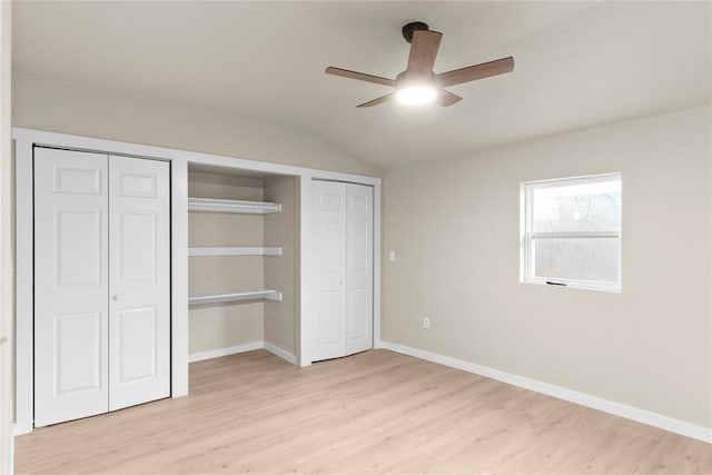 unfurnished bedroom featuring ceiling fan, vaulted ceiling, multiple closets, and light hardwood / wood-style flooring