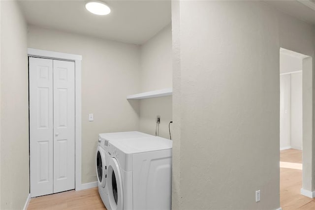 laundry area featuring washing machine and clothes dryer and light wood-type flooring