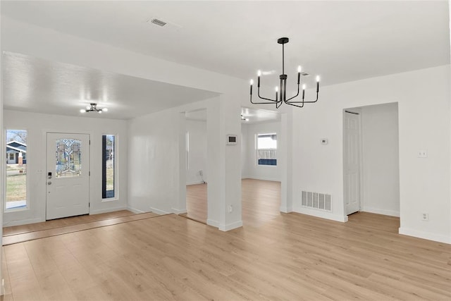 entryway featuring visible vents, baseboards, light wood-style floors, and a notable chandelier