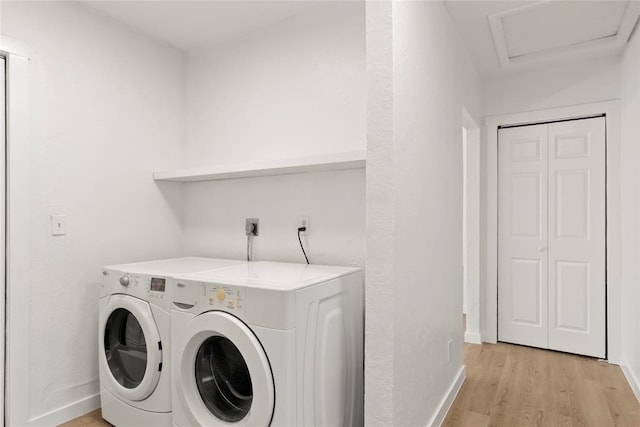 laundry area featuring attic access, separate washer and dryer, light wood-type flooring, and baseboards