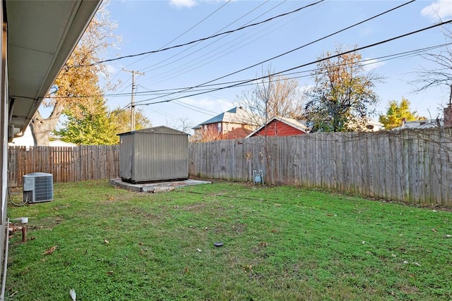 view of yard featuring a fenced backyard, a storage unit, central AC, and an outdoor structure