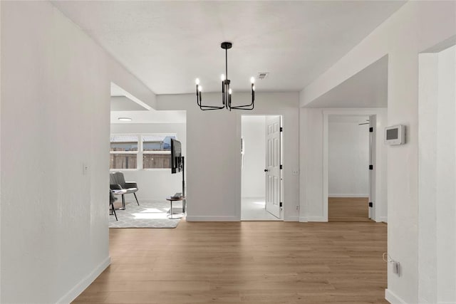 unfurnished dining area with visible vents, baseboards, light wood-type flooring, and a chandelier