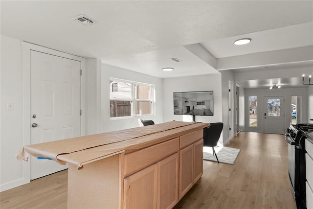 kitchen featuring light wood-style flooring, gas stove, visible vents, and light brown cabinetry