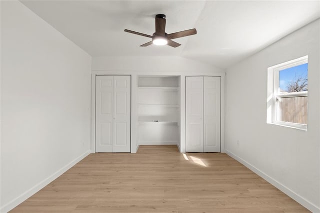 unfurnished bedroom featuring a closet, light wood-style flooring, lofted ceiling, and baseboards