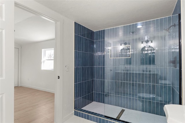 bathroom featuring baseboards, tiled shower, and wood finished floors