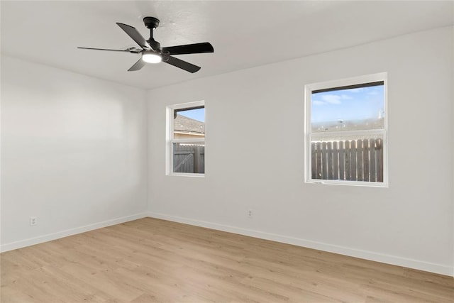 spare room with baseboards, light wood-style flooring, and a ceiling fan