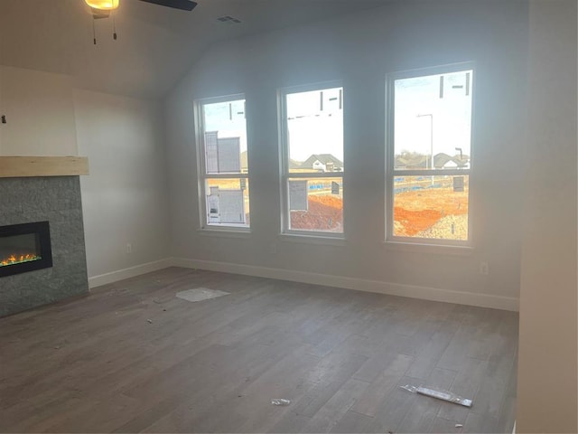 unfurnished living room featuring hardwood / wood-style floors, a stone fireplace, and a wealth of natural light