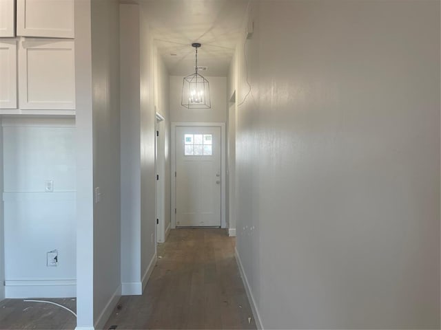 hallway featuring an inviting chandelier and dark hardwood / wood-style floors