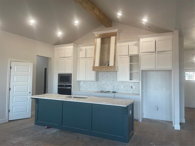 kitchen with vaulted ceiling with beams, white cabinetry, a center island with sink, oven, and wall chimney range hood