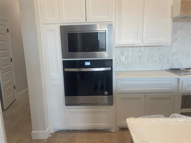 kitchen with white cabinetry, wall chimney range hood, and stainless steel appliances