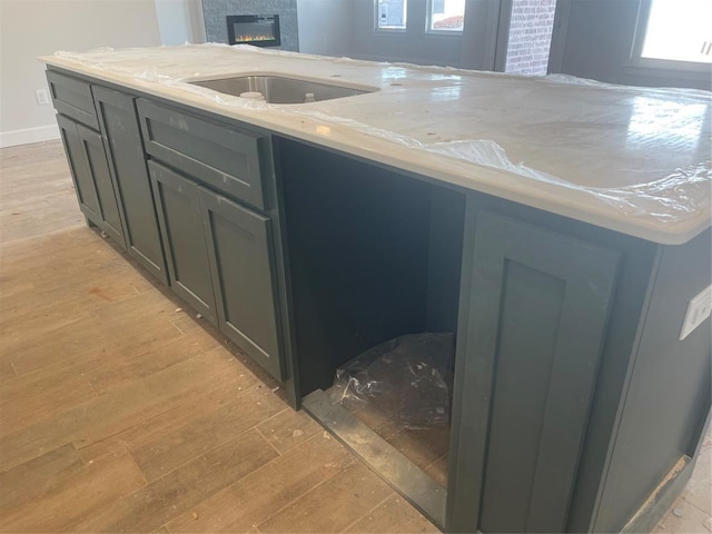 kitchen with light stone countertops, sink, and light wood-type flooring