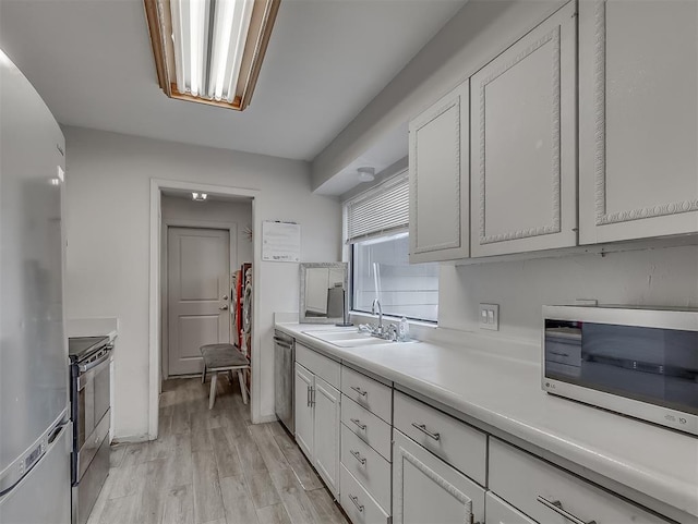 kitchen with white cabinetry, sink, appliances with stainless steel finishes, and light hardwood / wood-style flooring