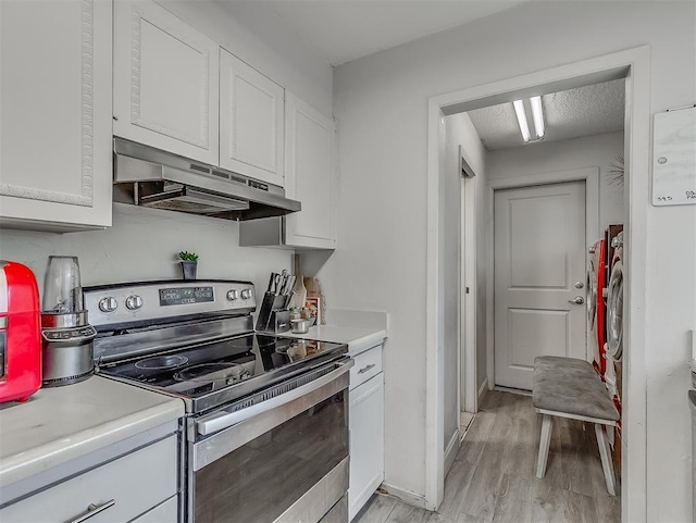 kitchen with a textured ceiling, light hardwood / wood-style floors, white cabinetry, and electric stove