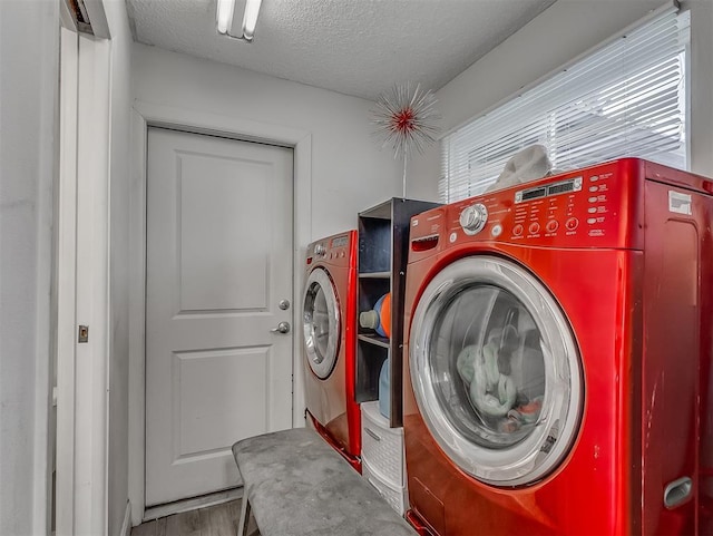 laundry room with washing machine and clothes dryer, hardwood / wood-style floors, and a textured ceiling