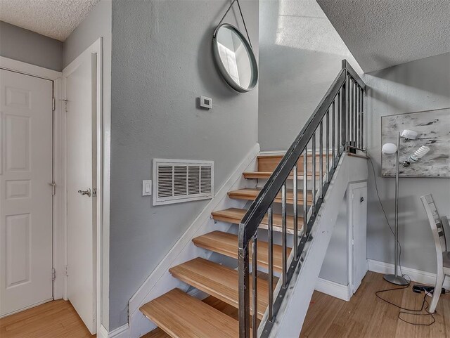 stairway featuring hardwood / wood-style floors and a textured ceiling