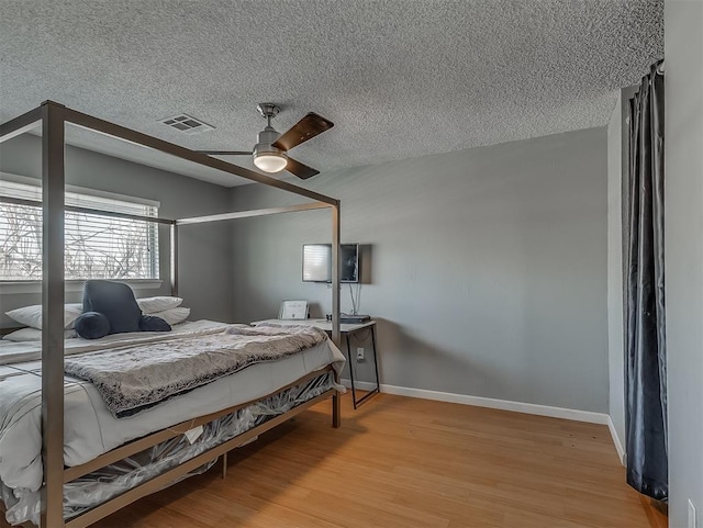 bedroom with ceiling fan, a textured ceiling, and light wood-type flooring