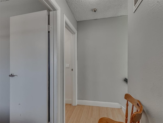 corridor featuring a textured ceiling and light hardwood / wood-style flooring