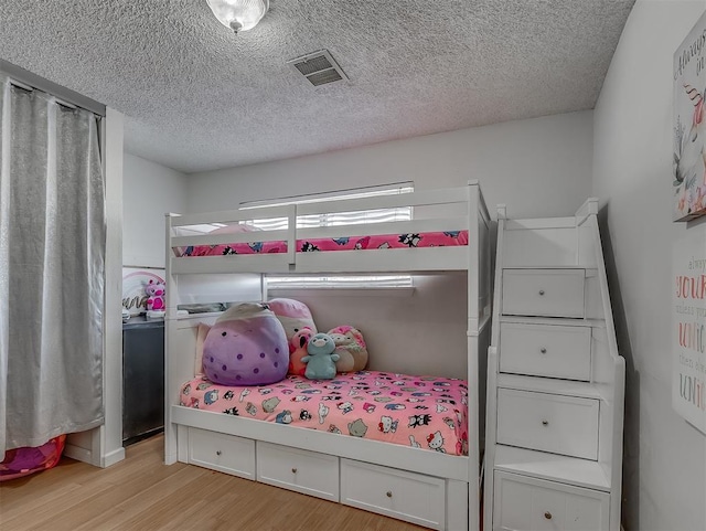 bedroom with a textured ceiling and light hardwood / wood-style flooring