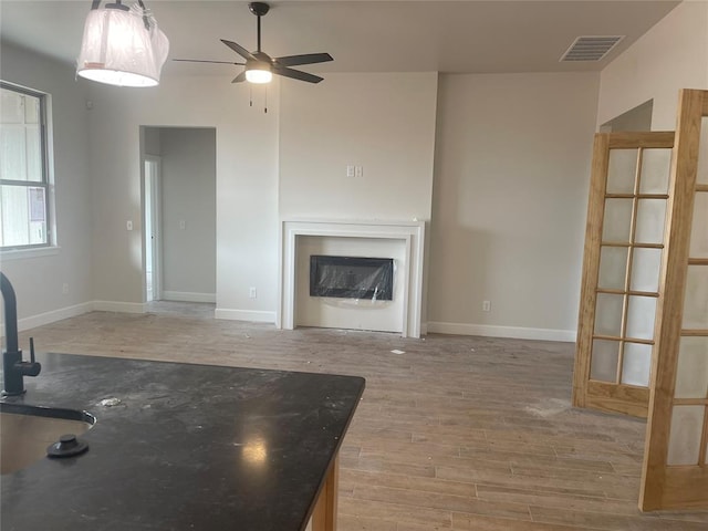 unfurnished living room with ceiling fan and wood-type flooring